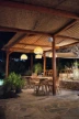 Outdoor dining area with wooden tables and chairs at night.